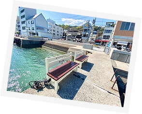 写真：港の景色にアイスクリーム店のベンチが２つ写っています