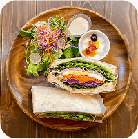 写真：木のプレートの上にサンドイッチとサラダとデザート