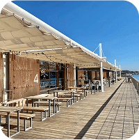 写真：海沿いのカフェテラス。沢山のテーブルとベンチ