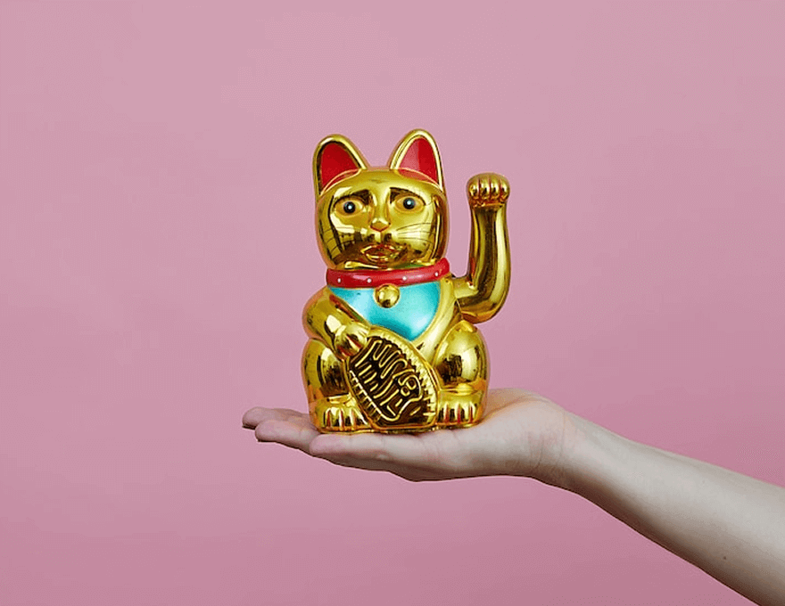 写真:手のひらの上に金色の招き猫の貯金箱